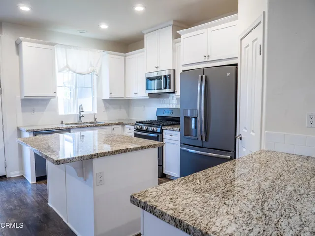 a kitchen with stainless steel appliances granite countertop a refrigerator a stove a sink a microwave and cabinets