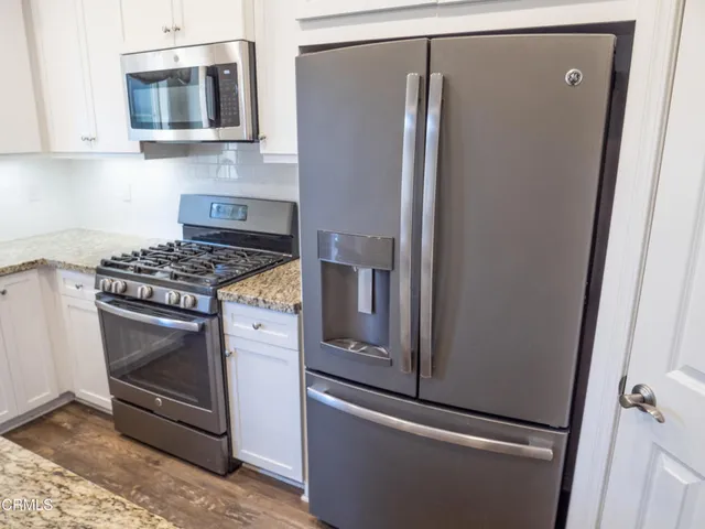 a kitchen with stainless steel appliances white cabinets and a stove top oven
