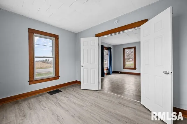 a view of an empty room with wooden floor and a window