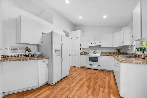 a kitchen with stainless steel appliances granite countertop a refrigerator a stove top oven a sink and dishwasher with wooden floor