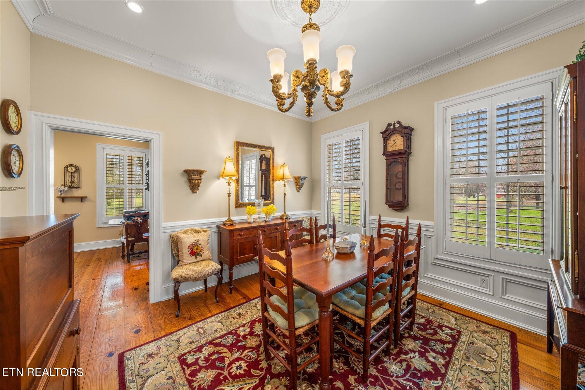 7016 Castlewood Road Knoxville, TN 37931 - Photo 17 of 58 a dining room with wooden floor a chandelier a wooden table and chairs