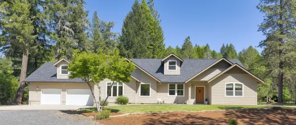 a front view of a house with a garden and trees