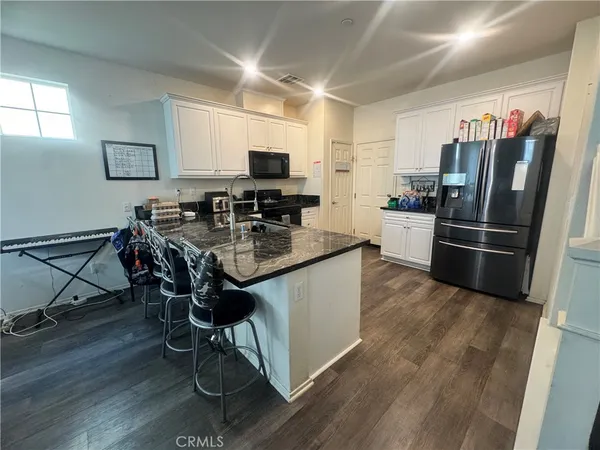 a kitchen with granite countertop a refrigerator stove and microwave
