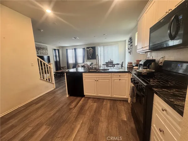 a kitchen with granite countertop stainless steel appliances a sink a stove top oven a counter space and cabinets