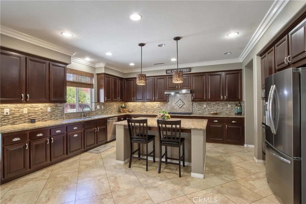 28483 Nautical Point Circle Menifee, CA 92585 - Photo 3 of 44 a kitchen with kitchen island granite countertop wooden cabinets and a refrigerator