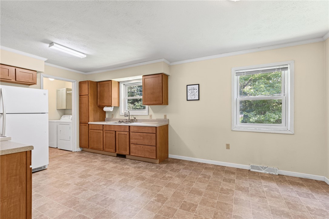 322 Tribble Street Honea Path, SC 29654 - Photo 10 of 35 Ample wooden cabinetry and resilient tile-patterned flooring define this functional kitchen space.