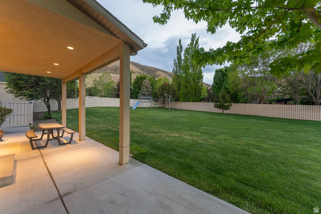 1712 Somerset Ridge Drive Draper, UT 84020 - Photo 70 of 76 Expansive backyard featuring a covered patio with recessed lighting, concrete flooring, a lush green lawn, and a light-toned privacy fence