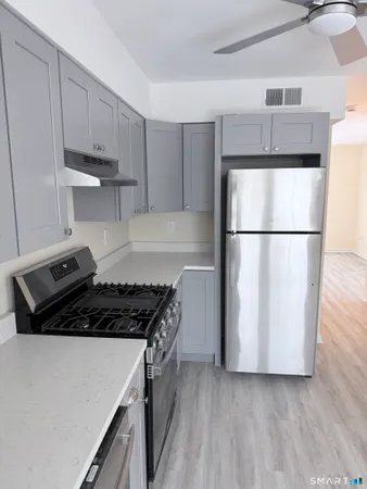 a kitchen with a refrigerator a stove and white cabinets