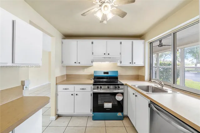 a kitchen with a refrigerator a sink and dishwasher with white cabinets
