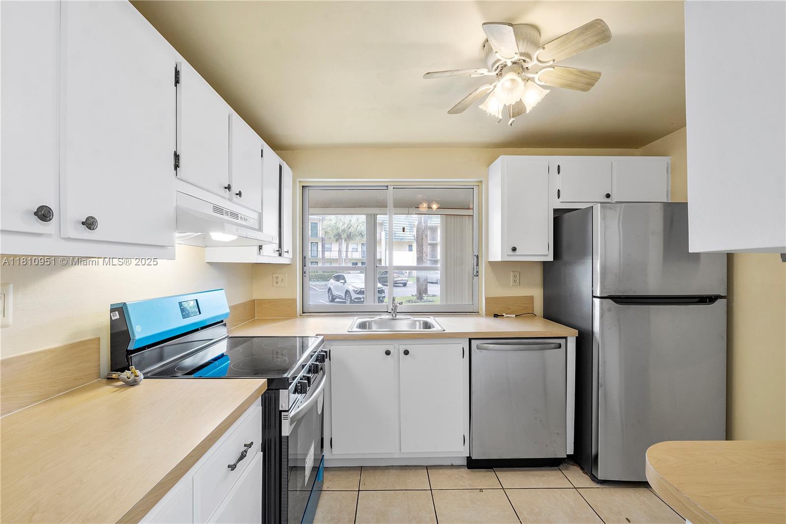 9091 Lime Bay Boulevard, Unit 110 Tamarac, FL 33321 - Photo 10 of 40 a kitchen with a sink a stove a refrigerator and white cabinets