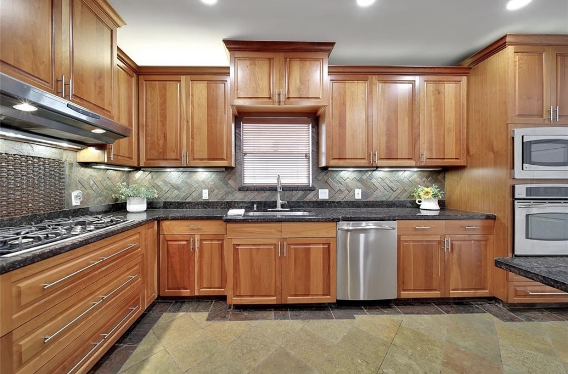 12922 Lentando Drive Cypress, TX 77429 - Photo 3 of 41 a kitchen with granite countertop wooden cabinets a sink and dishwasher