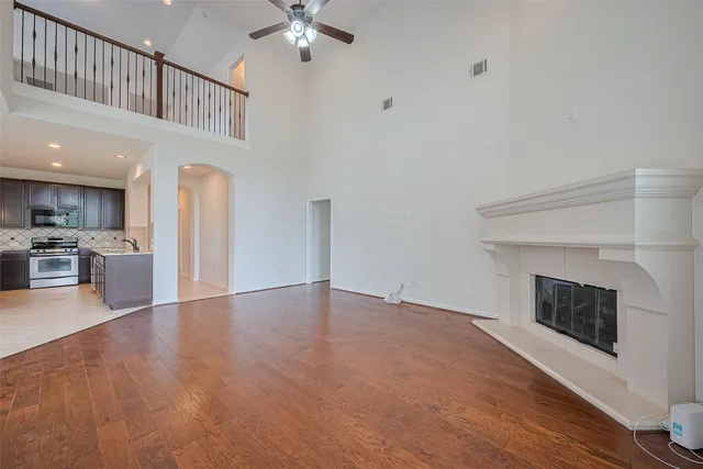 a view of an empty room with wooden floor and a fireplace