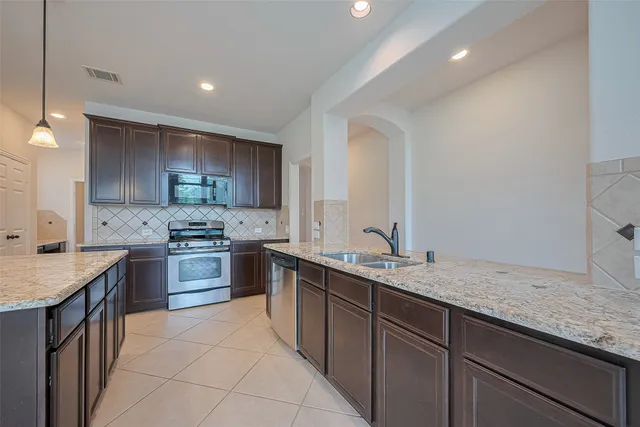 a kitchen with stainless steel appliances granite countertop a sink stove and refrigerator