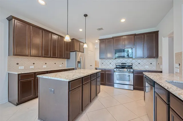 a kitchen with stainless steel appliances granite countertop a stove a sink dishwasher a refrigerator and a oven with wooden floor