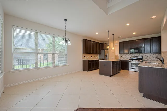 a large kitchen with a large counter top stainless steel appliances and cabinets