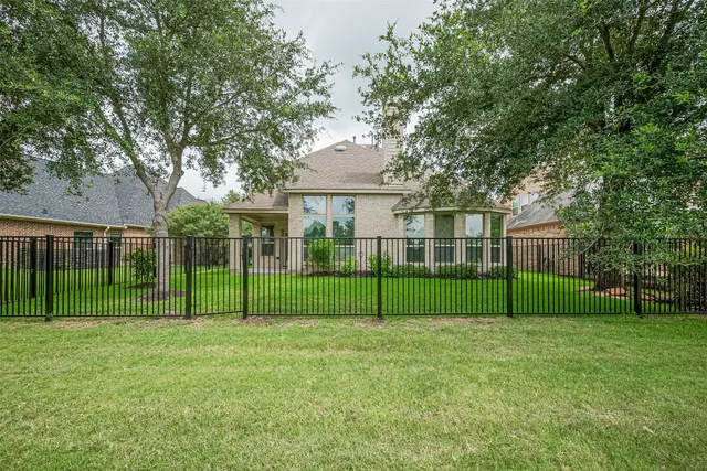 a view of a house next to a big yard and large trees
