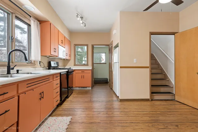 a large kitchen with stainless steel appliances granite countertop a sink and a wooden floors