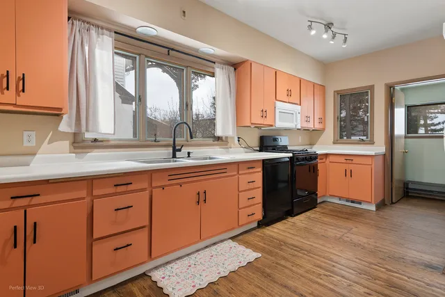 a kitchen with stainless steel appliances kitchen island granite countertop a sink cabinets wooden floor and a large window