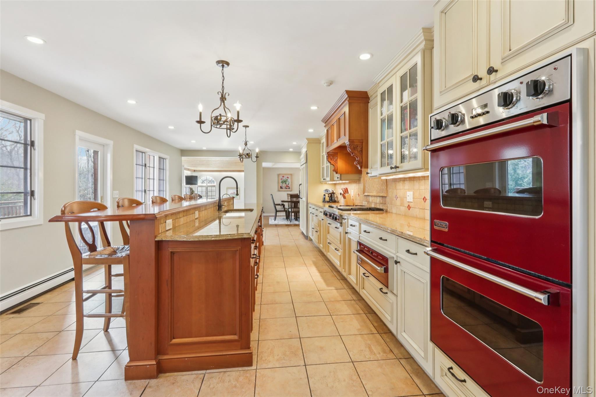 27 Cat Ridge Road North Salem, NY 10560 - Photo 22 of 46 Kitchen with multiple ovens, glass insert cabinets, a breakfast bar, a kitchen island with sink, and light stone counters