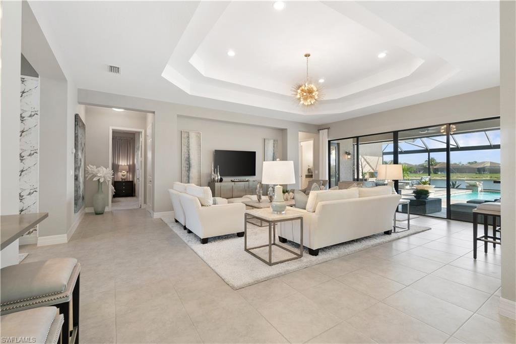 4467 Caldera Circle Naples, FL 34119 - Photo 11 of 50 a living room with furniture a chandelier and a dining table with a large window