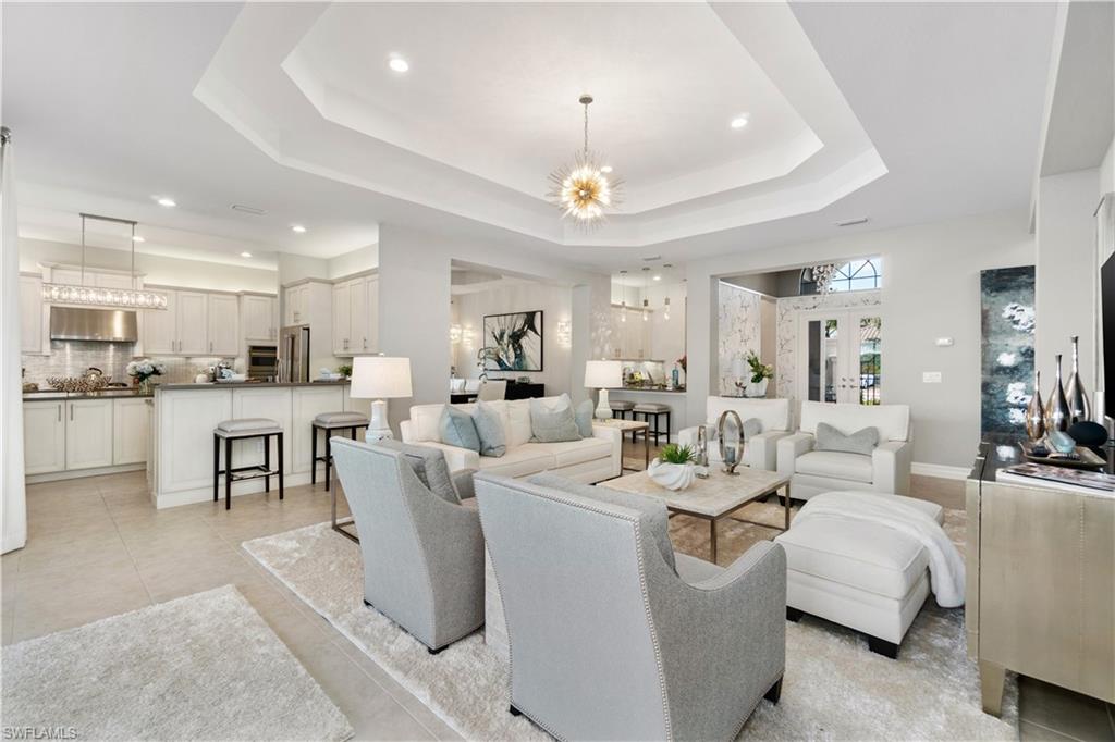 4467 Caldera Circle Naples, FL 34119 - Photo 12 of 50 a living room with couches a kitchen island a stove and a dining table with wooden floor