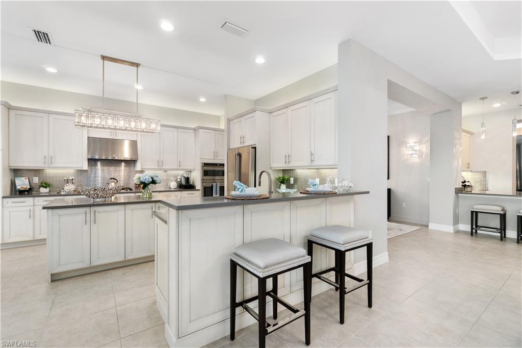 4467 Caldera Circle Naples, FL 34119 - Photo 17 of 50 a kitchen with stainless steel appliances granite countertop a table chairs sink refrigerator and cabinets