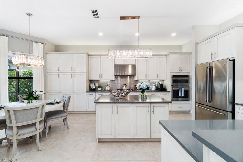4467 Caldera Circle Naples, FL 34119 - Photo 18 of 50 a kitchen with kitchen island a sink counter and chairs
