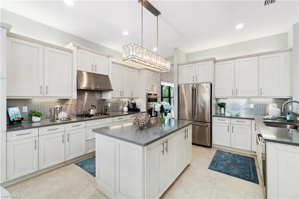 4467 Caldera Circle Naples, FL 34119 - Photo 19 of 50 a kitchen with kitchen island granite countertop a sink cabinets stainless steel appliances and a counter top space