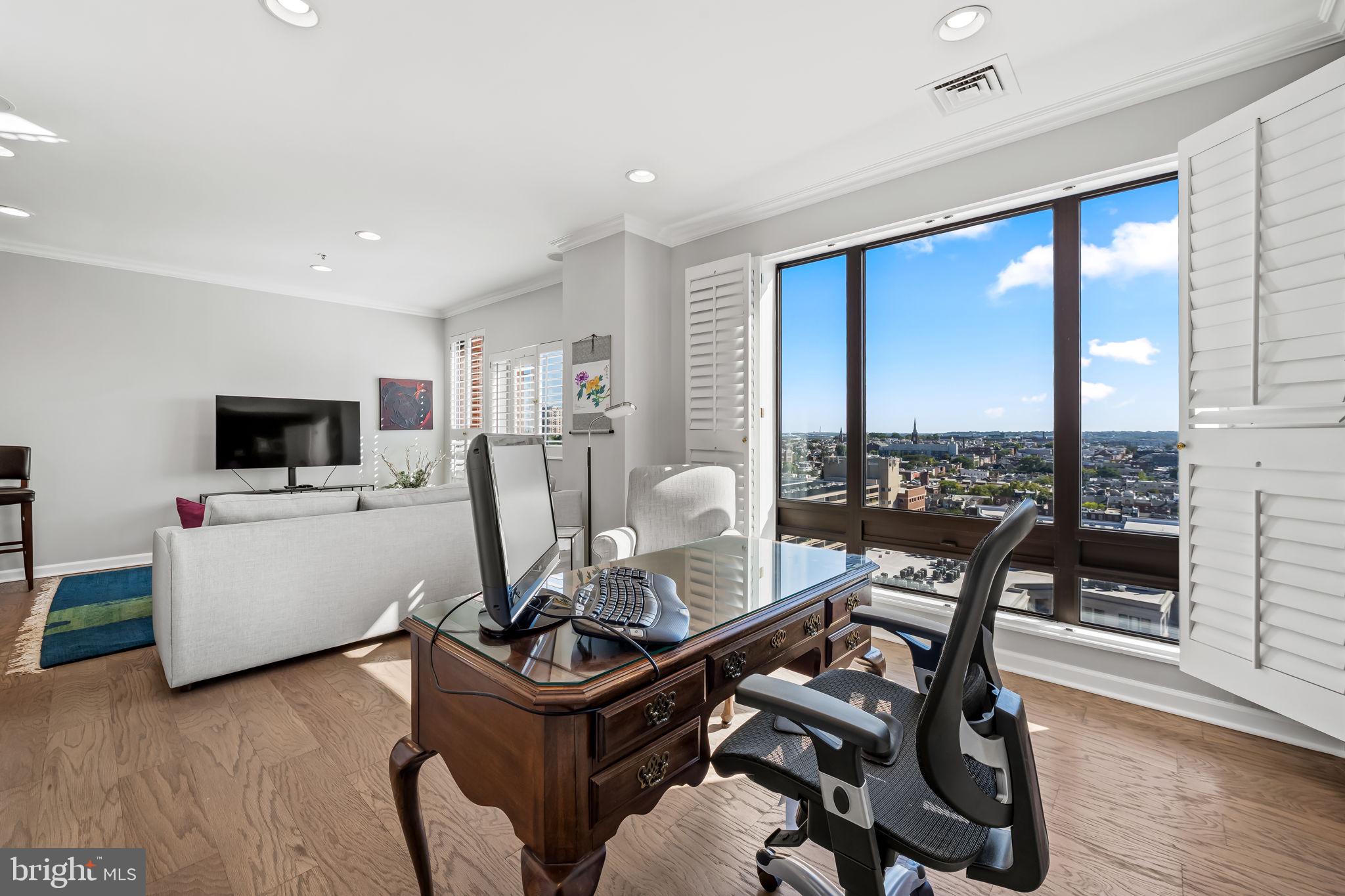 10 East Lee Street, Unit 1103 Baltimore, MD 21202 - Photo 15 of 42 a living room with furniture a flat screen tv and a floor to ceiling window