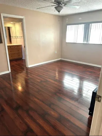 a view of empty room with wooden floor and fan