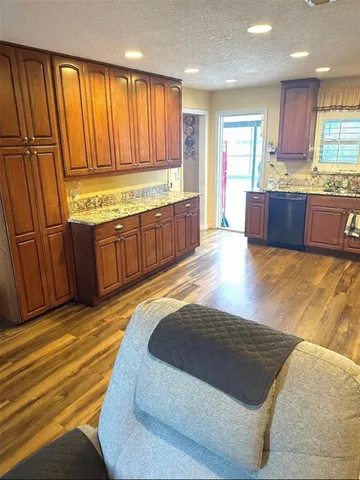 a large kitchen with kitchen island granite countertop wooden cabinets a sink and a stainless steel appliances