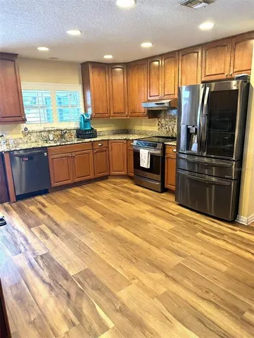 a kitchen with stainless steel appliances kitchen island granite countertop a stove top oven and sink