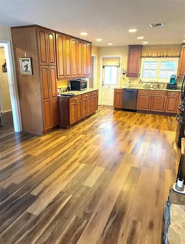 a large kitchen with stainless steel appliances wooden floors and large window