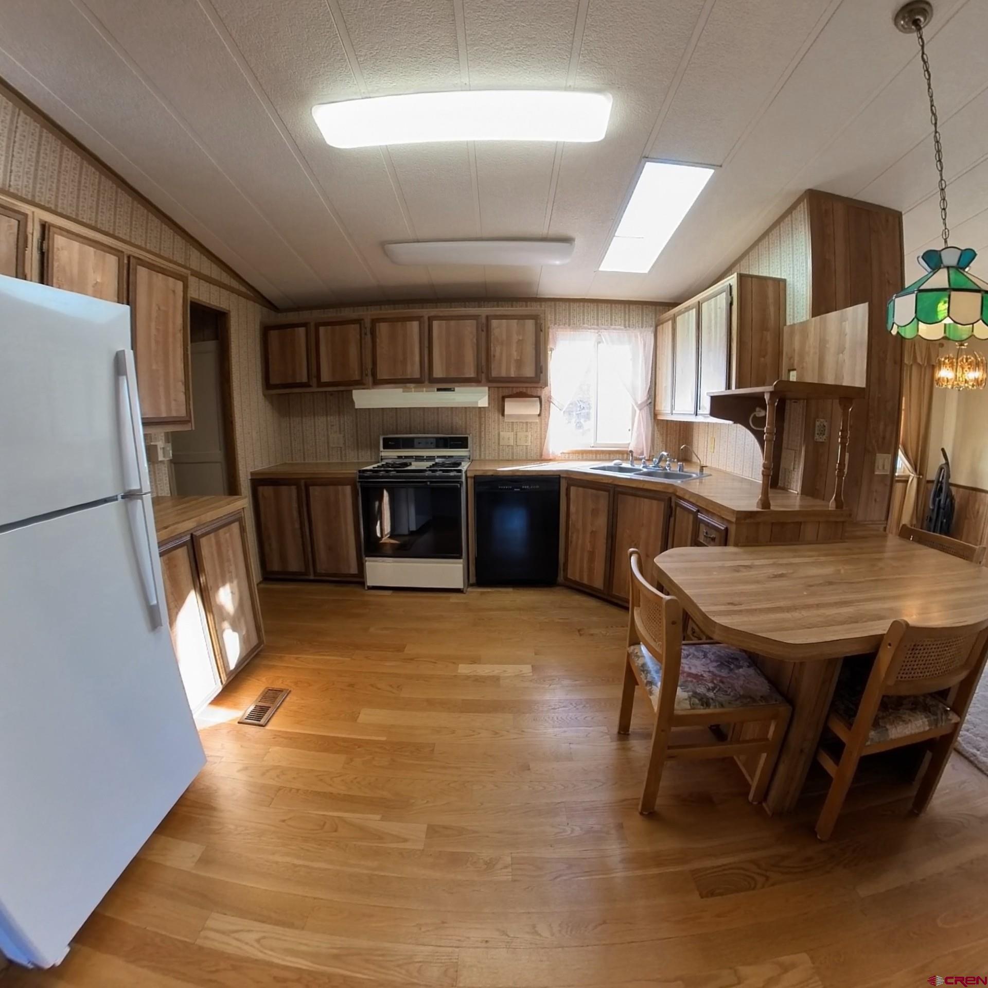 18865 Northridge Road Cedaredge, CO 81413 - Photo 10 of 23 a kitchen with stainless steel appliances granite countertop a stove a refrigerator a sink dishwasher a dining table and chairs with wooden floor