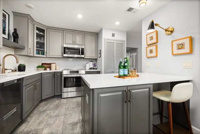 a kitchen with stainless steel appliances a stove a sink a microwave a refrigerator and cabinets