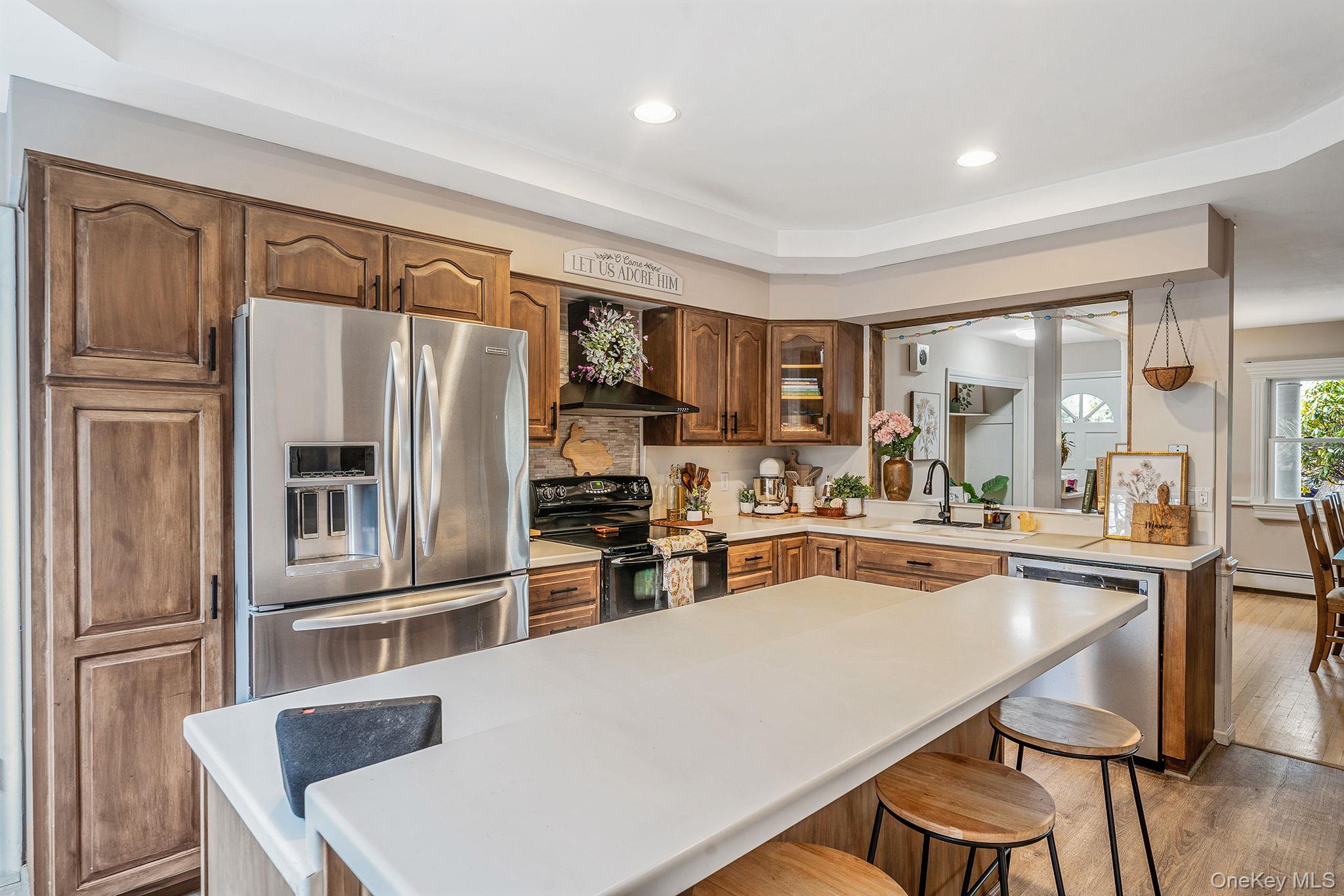 23 Wylde Road Mount Sinai, NY 11766 - Photo 11 of 45 a kitchen with stainless steel appliances a refrigerator a stove a sink dishwasher a dining table and chairs with wooden floor