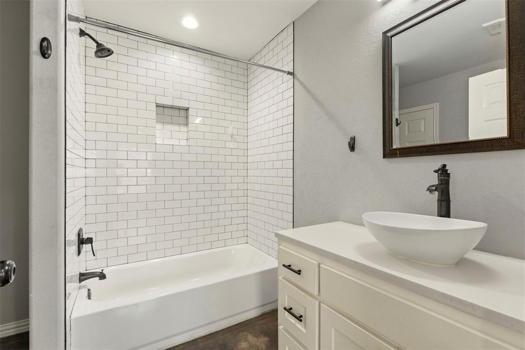 933 Rice Street Denison, TX 75020 - Photo 9 of 19 a bathroom with a bathtub shower sink and mirror