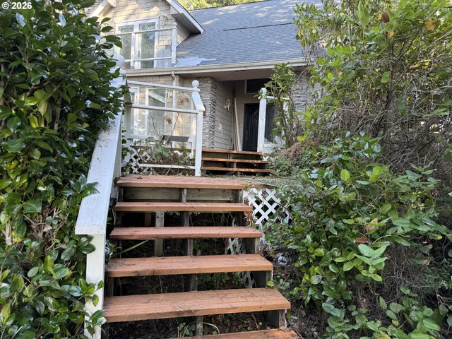 a view of a white house with large windows and a tree