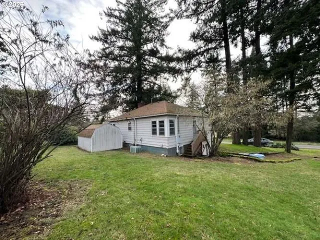 a house that is sitting in the grass with large trees