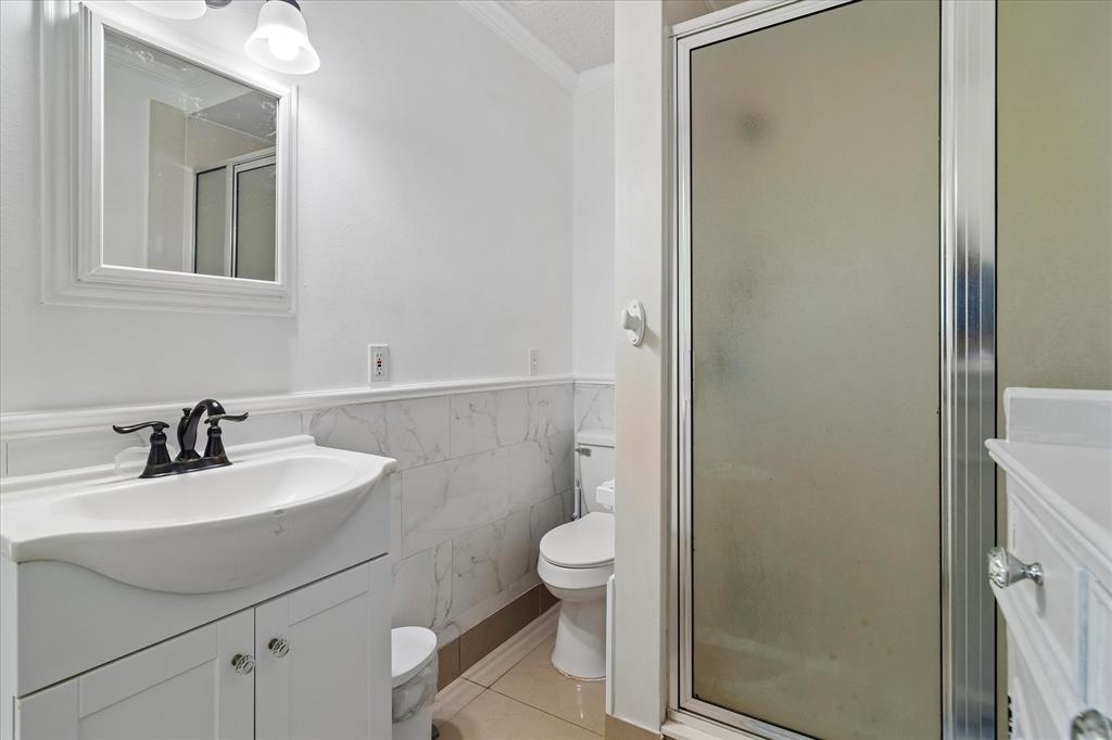 3007 McReynolds Road Sanger, TX 76266 - Photo 29 of 39 Bathroom featuring a vanity with an integrated sink and black faucet, a framed mirror, and a walk-in shower with a frosted glass door