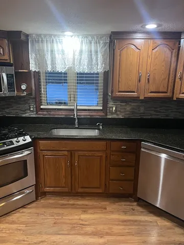 a kitchen with stainless steel appliances granite countertop a stove a sink and a microwave