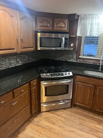 a kitchen with granite countertop a stove and a microwave