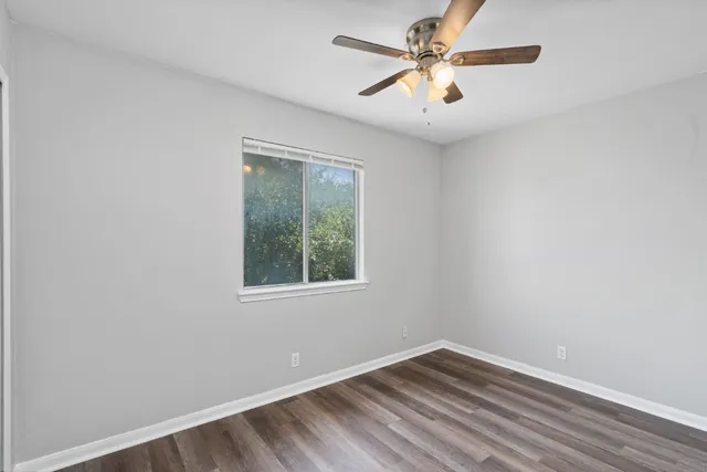 an empty room with windows and fan