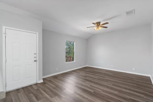 an empty room with wooden floor and windows