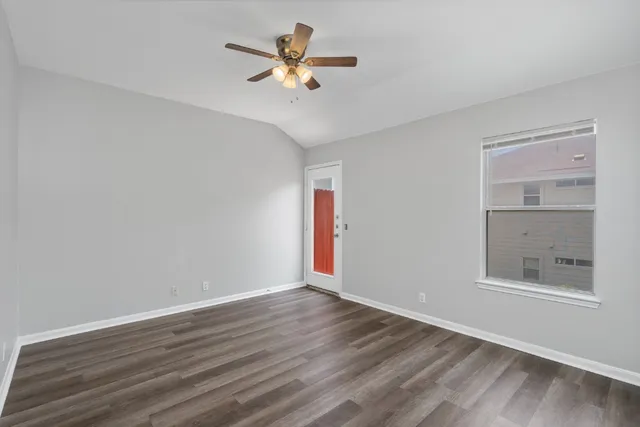 a view of an empty room with a window and wooden floor