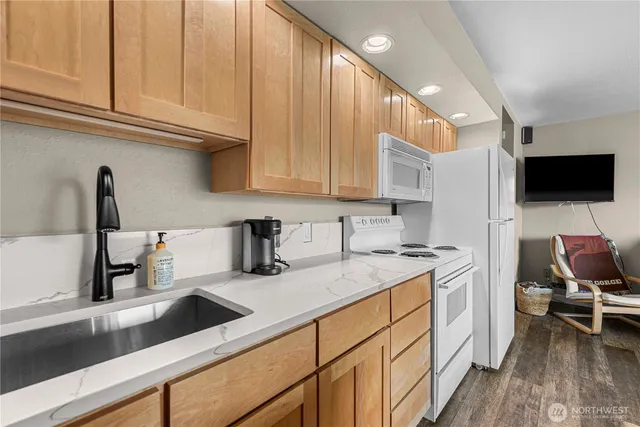 a kitchen with a sink dishwasher and white cabinets with wooden floor