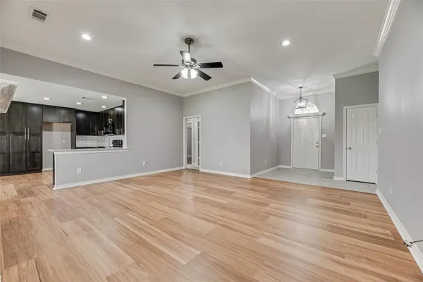 a view of an empty room with kitchen and a window