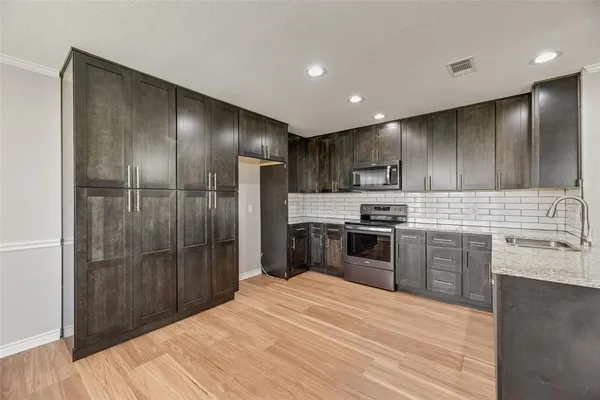 a kitchen with granite countertop stainless steel appliances cabinets a sink and a counter top space
