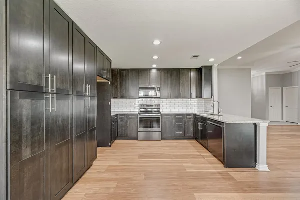 a large kitchen with stainless steel appliances granite countertop a large counter top a stove and a refrigerator