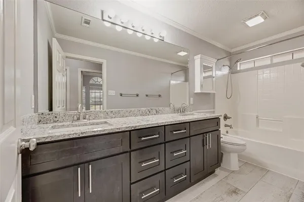 a bathroom with a granite countertop sink a toilet a mirror and shower